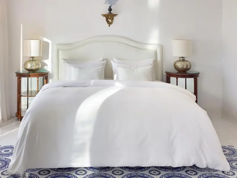 Un lit blanc dans une chambre lumineuse avec des tables de chevet et des lampes.
