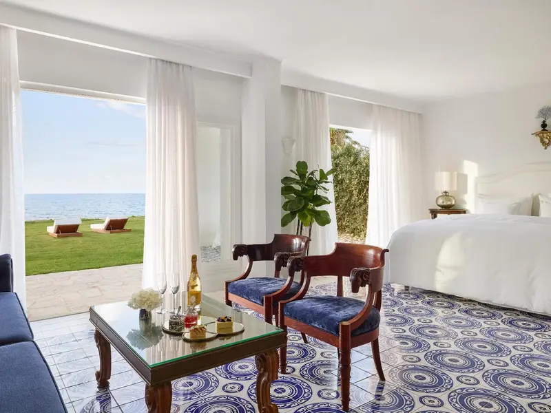 Une chambre lumineuse s'ouvre sur une vue mer et une pelouse.