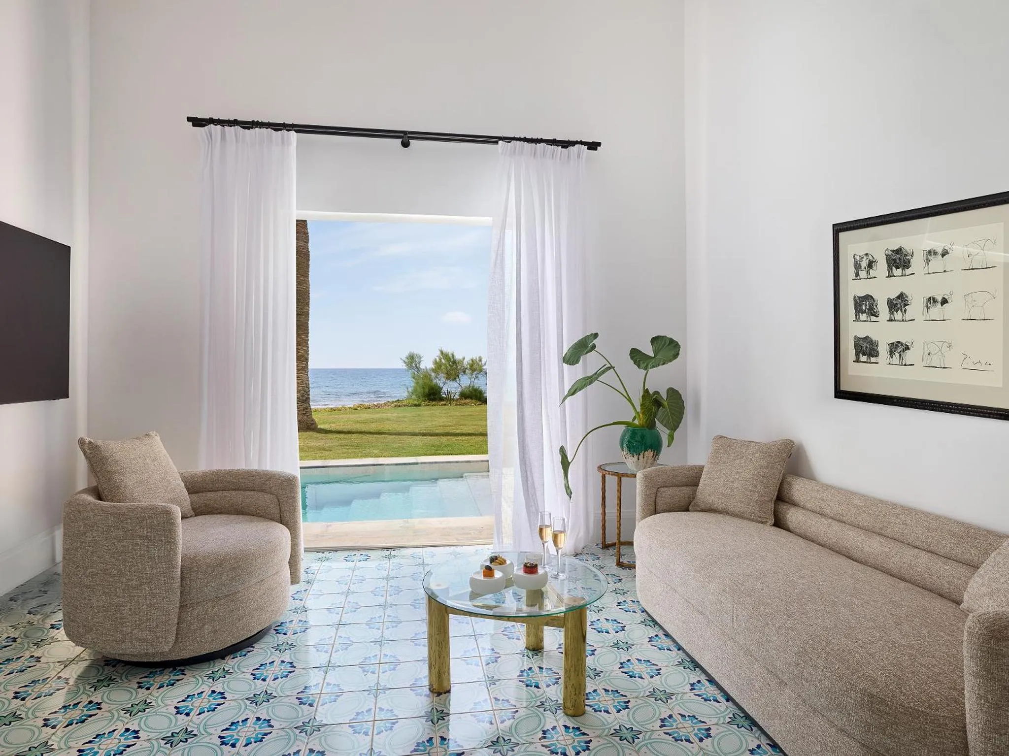 Un salon lumineux s'ouvre sur une terrasse avec piscine et vue sur la mer.