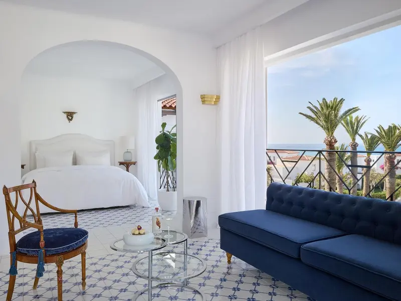 Une chambre lumineuse avec un coin salon donnant sur une vue sur la mer.