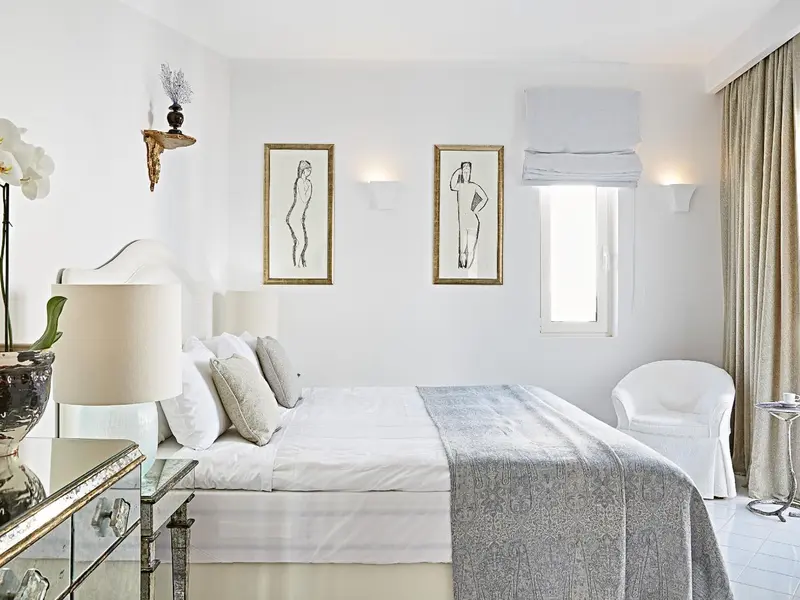 Une chambre lumineuse avec un grand lit et des œuvres d'art au mur.