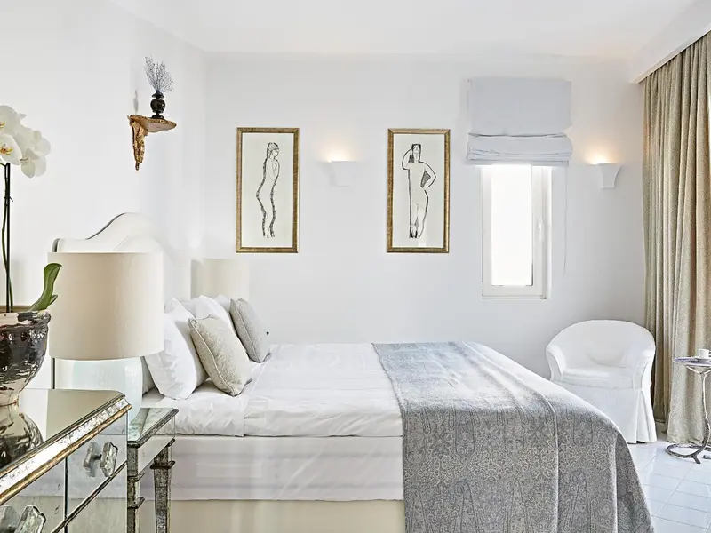 Une chambre lumineuse avec un grand lit et des œuvres d'art murales.