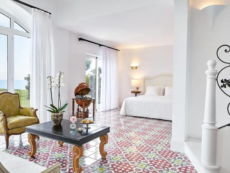 Une chambre lumineuse avec un lit blanc et un sol carrelé décoratif.