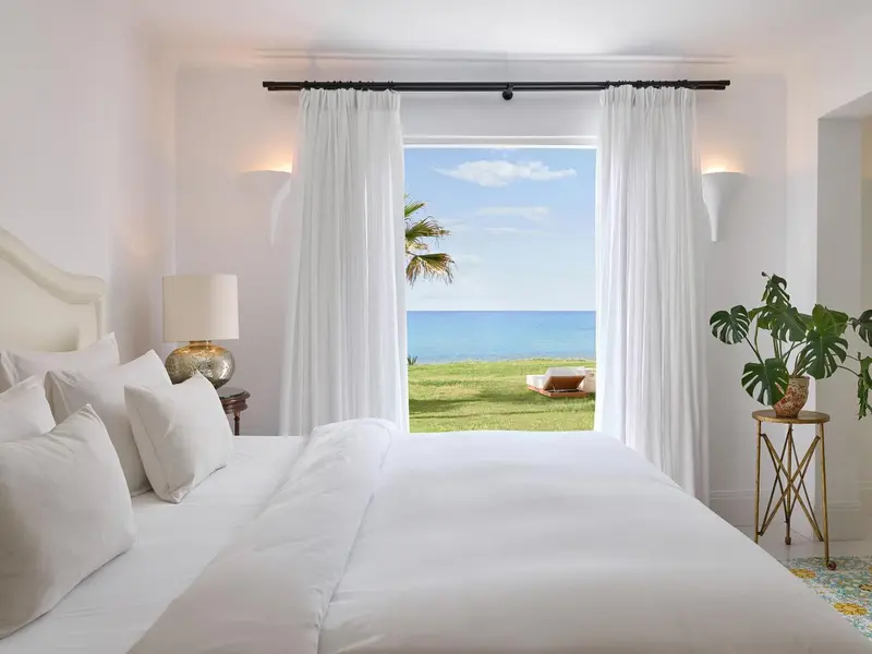 Une chambre lumineuse donne sur une vue mer et une pelouse verdoyante.