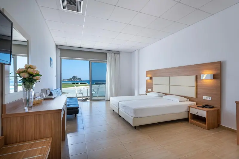 Chambre lumineuse avec un grand lit et une vue sur la mer.