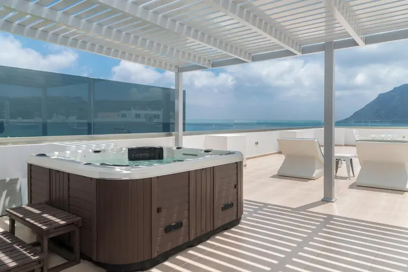 Un jacuzzi sur une terrasse avec vue sur la mer et les montagnes.