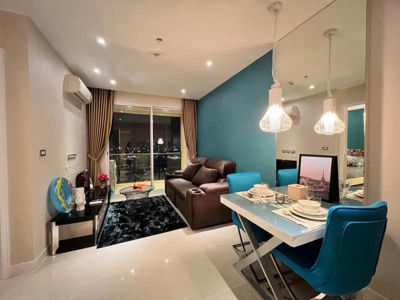 Un salon moderne avec un canapé marron et une table à manger éclairée par des suspensions.