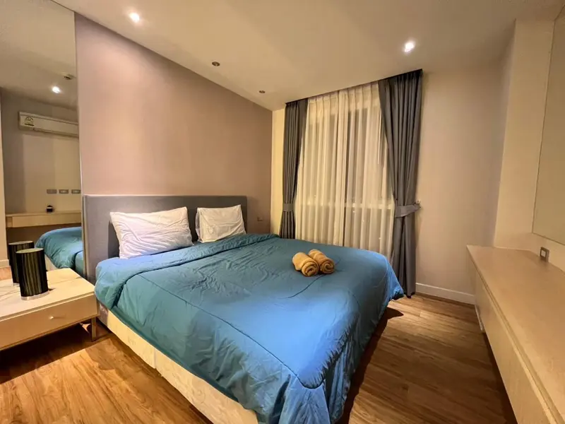 Une chambre lumineuse avec un grand lit recouvert d'une couette turquoise et de coussins blancs.