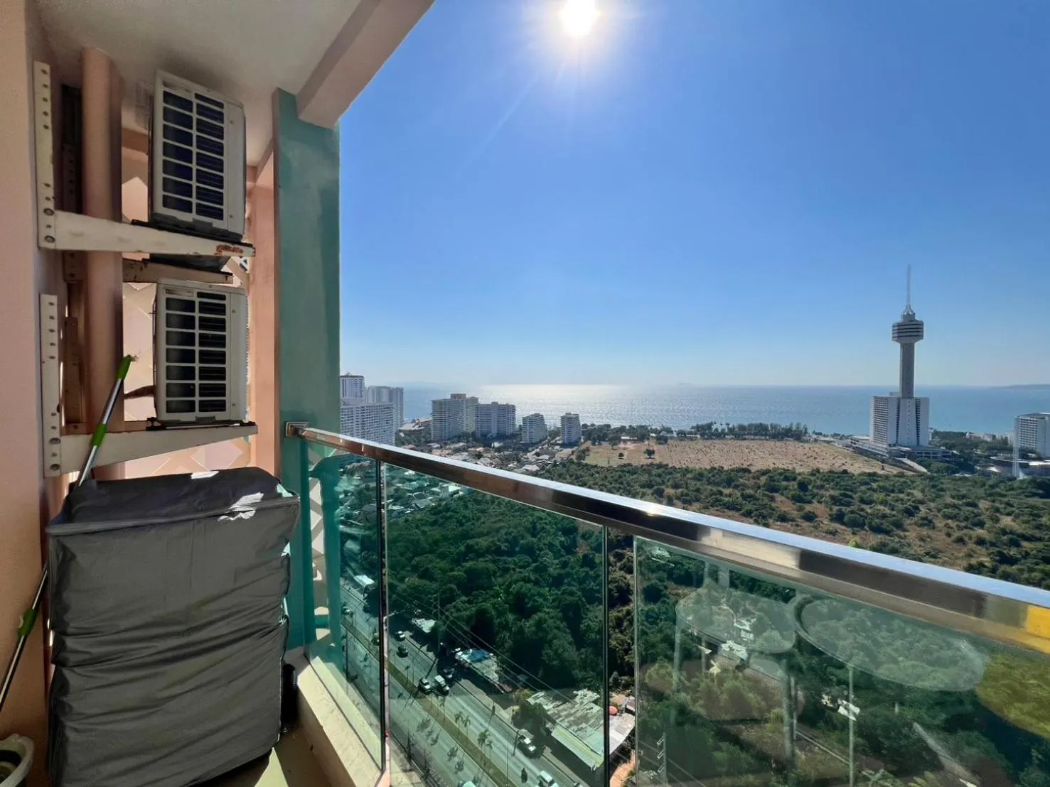 Vue d'un balcon avec garde-corps en verre donnant sur la mer et la ville.