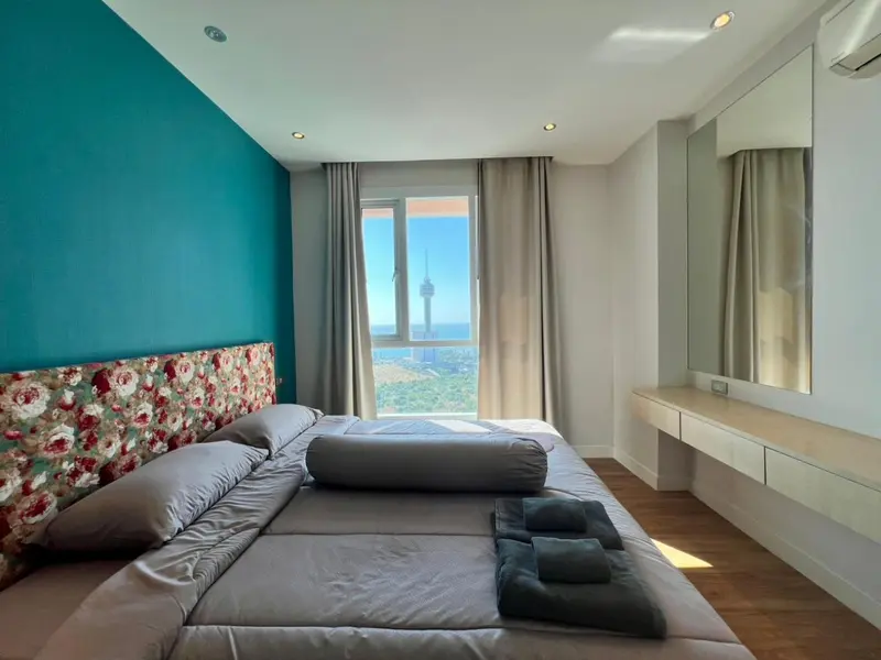 Une chambre lumineuse avec un grand lit et une vue sur la ville.
