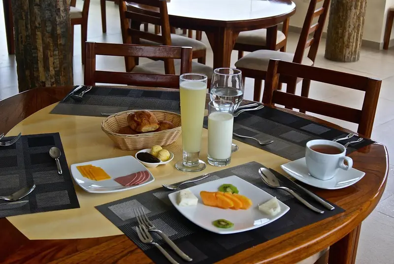 Une table ronde est dressée pour le petit-déjeuner avec des viennoiseries, des fruits et des boissons.