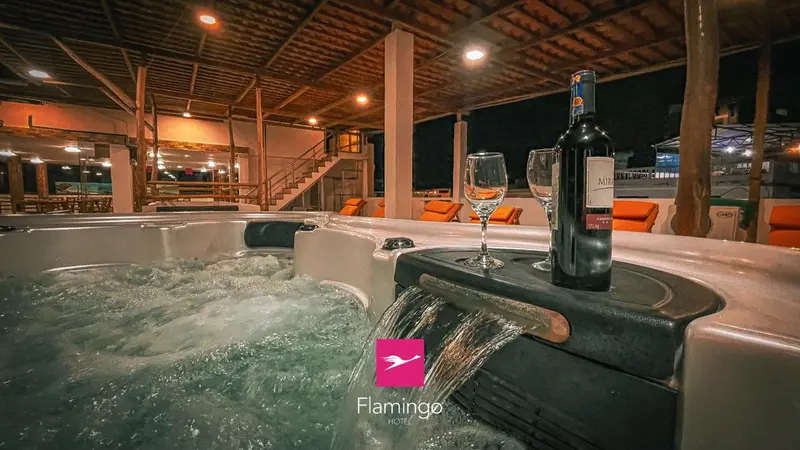 Un jacuzzi avec des verres et une bouteille de vin sur une terrasse éclairée.