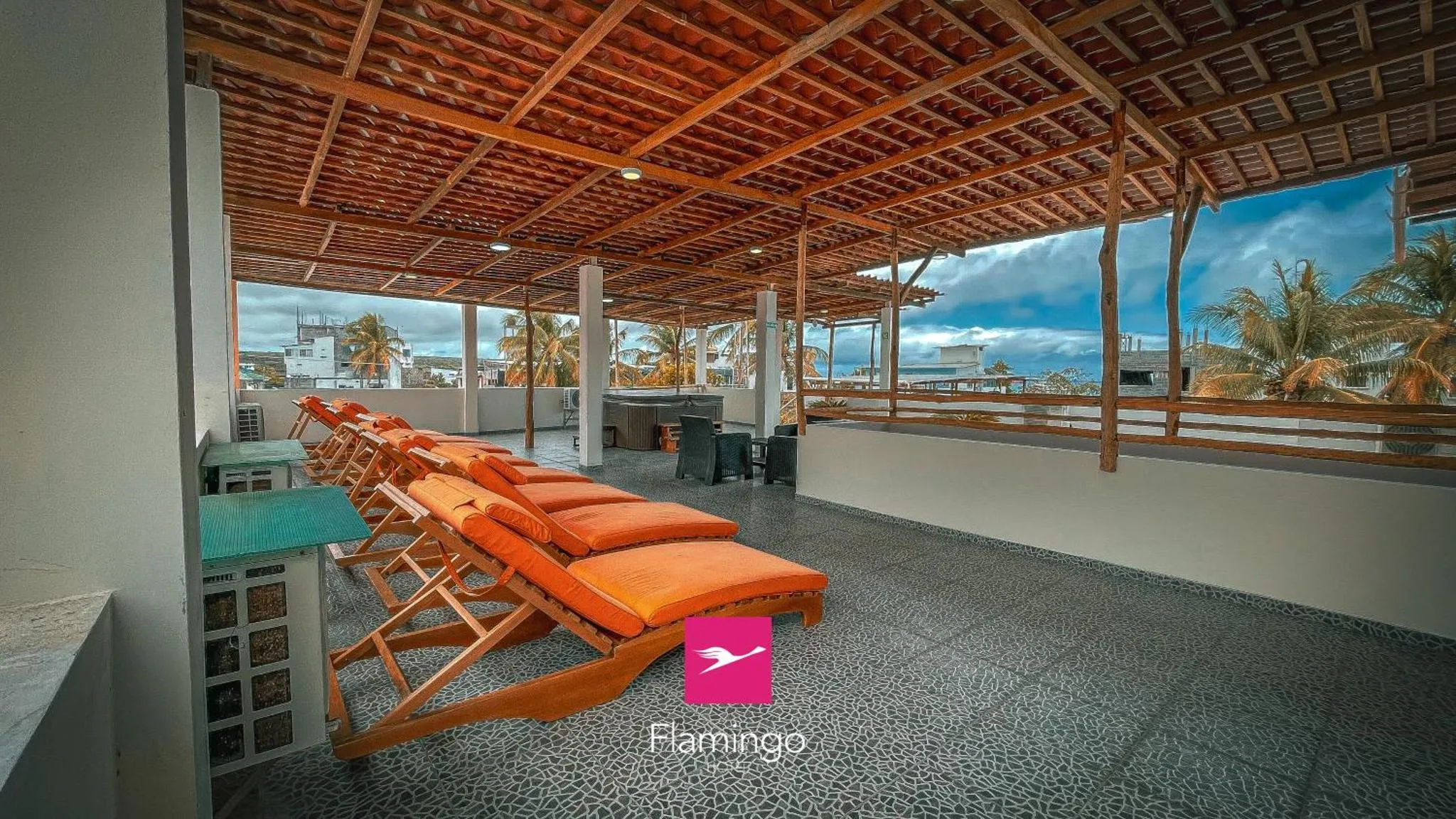 Transats orange disposés sur une terrasse ombragée avec vue sur la mer et la végétation.
