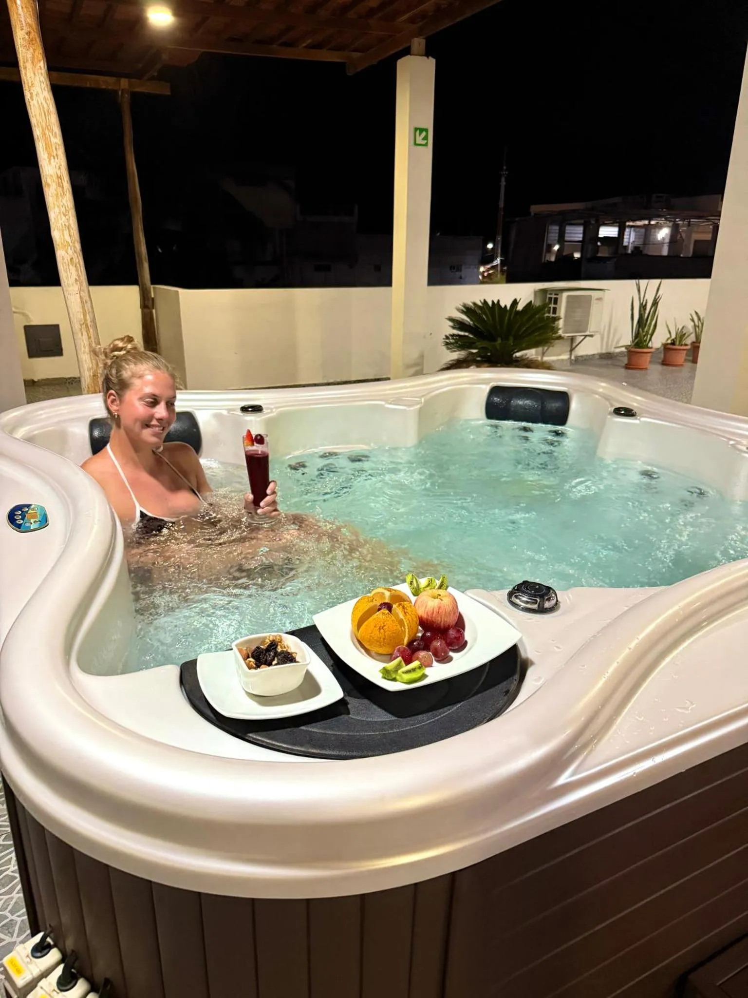 Une personne se détend dans un jacuzzi avec des fruits et une boisson.
