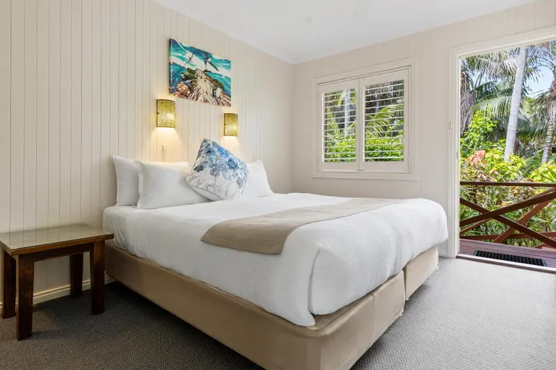 Une chambre lumineuse avec un grand lit recouvert d'une courtepointe et d'oreillers.
