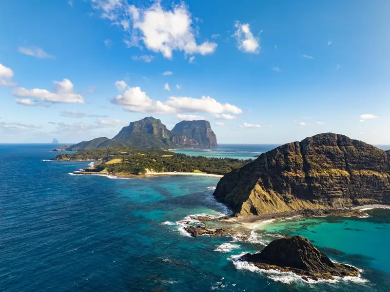 Vue aérienne d'une côte rocheuse et d'îlots verdoyants dans une mer turquoise.