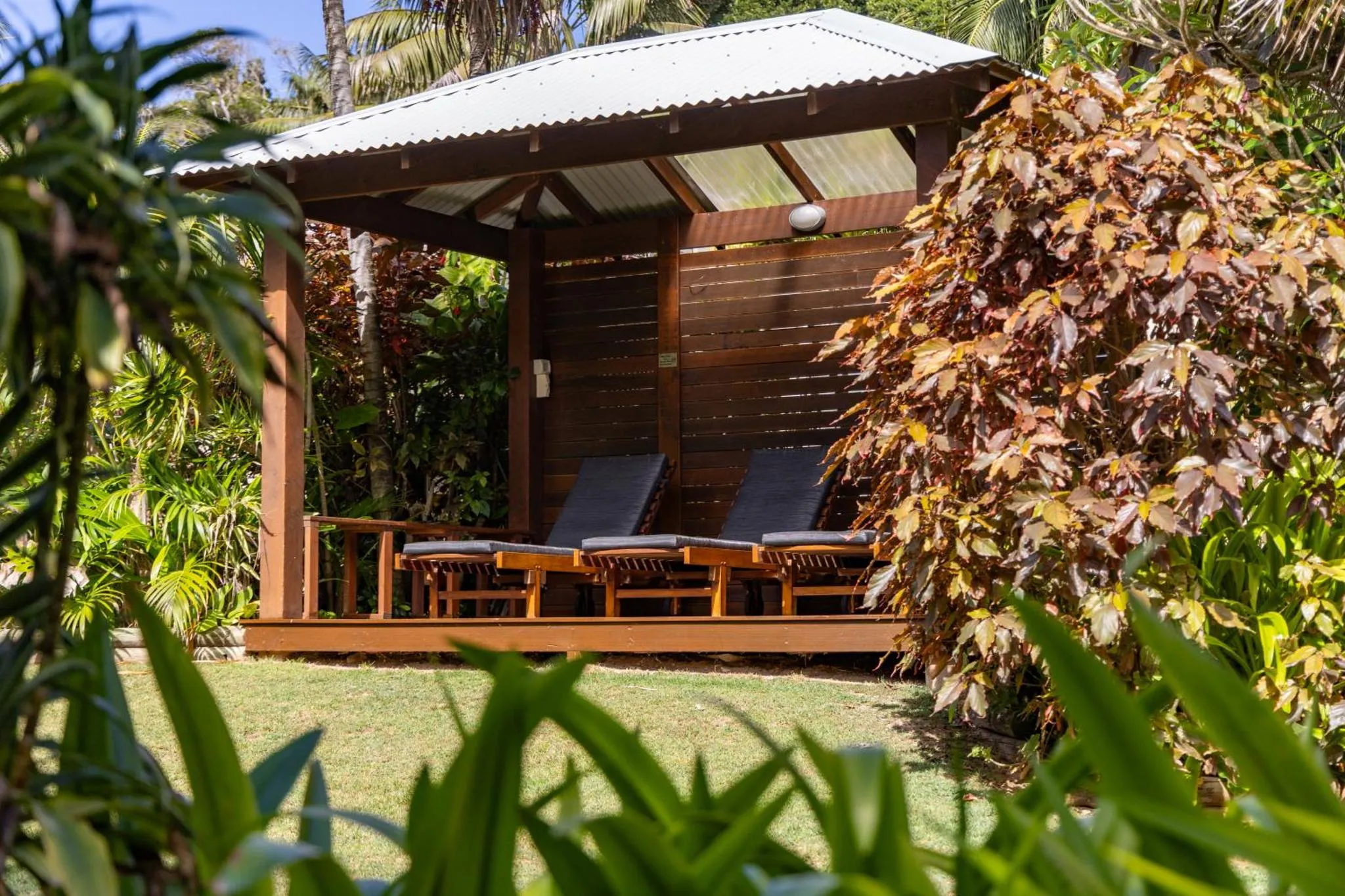 Deux fauteuils de jardin sont installés sur une terrasse en bois ombragée.
