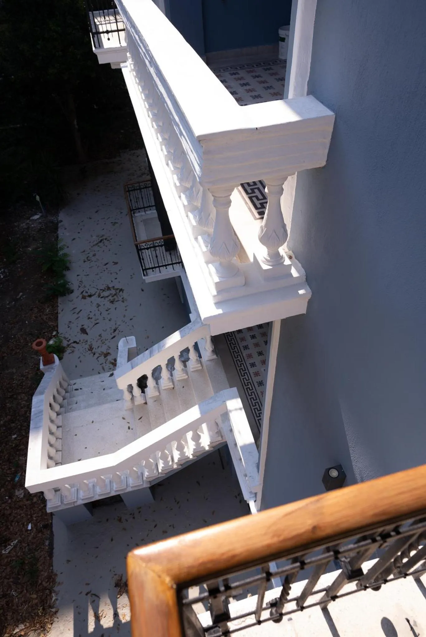 Escalier blanc en pierre menant à une terrasse avec garde-corps en bois.