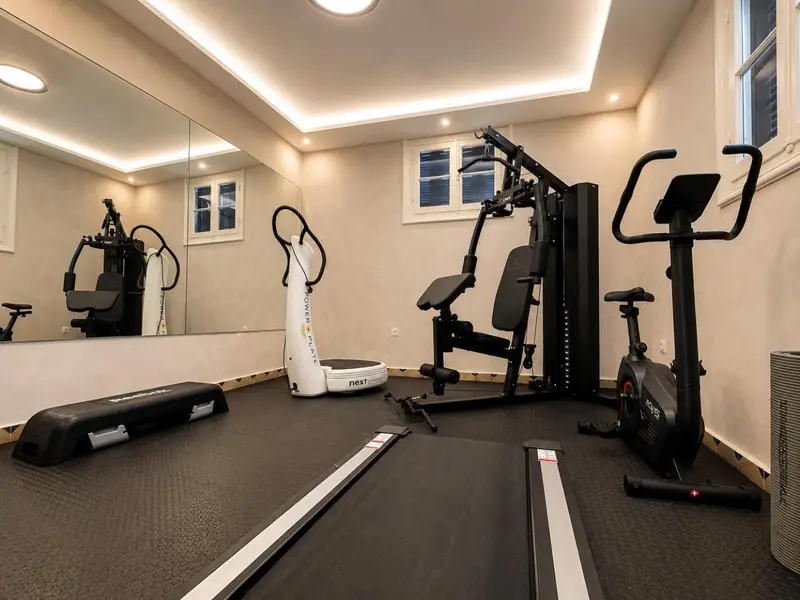 Une salle de sport lumineuse avec plusieurs appareils de fitness et un sol amortissant.