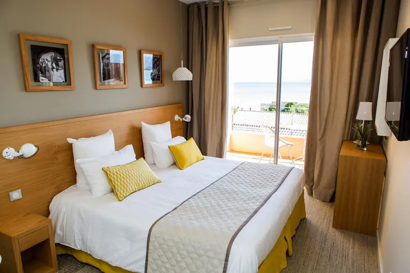 Une chambre lumineuse avec un grand lit et une vue sur la mer.