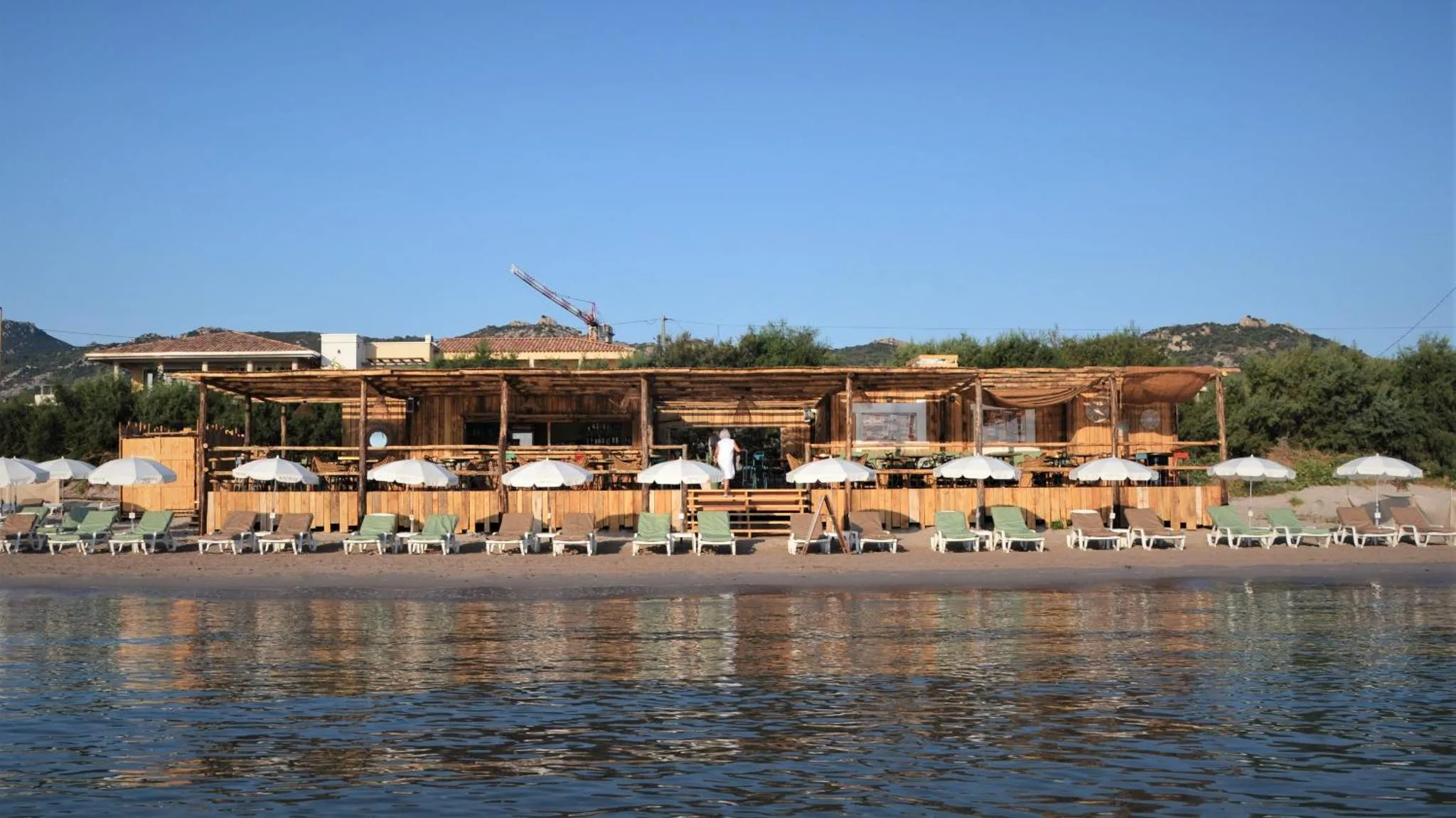 Terrasse de plage avec transats et parasols face à la mer.