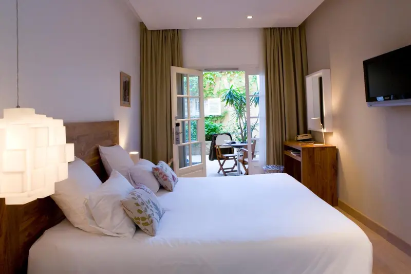 Une chambre lumineuse avec un lit recouvert d'oreillers et une terrasse verdoyante.