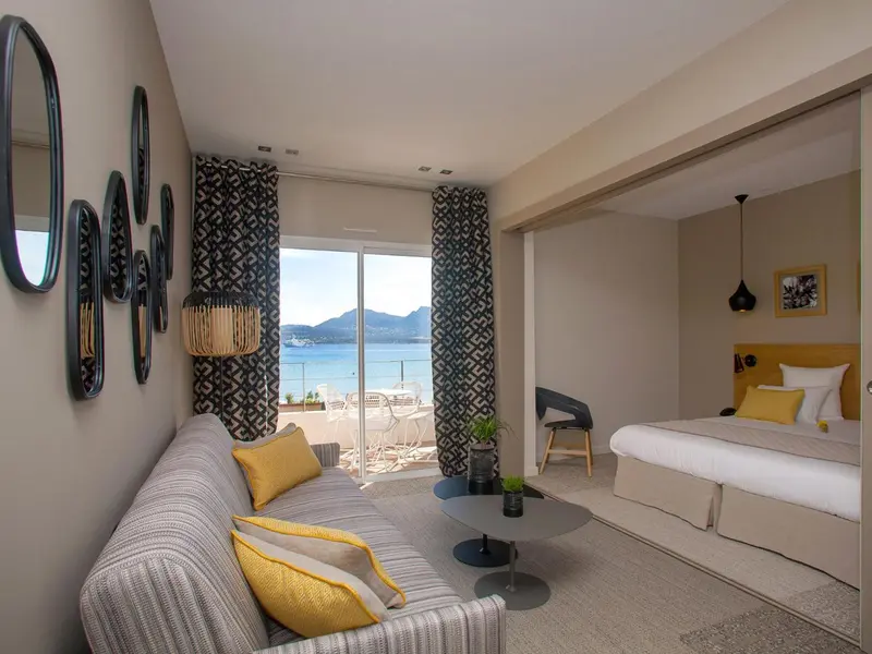 Un salon lumineux s'ouvre sur une chambre avec vue sur la mer.