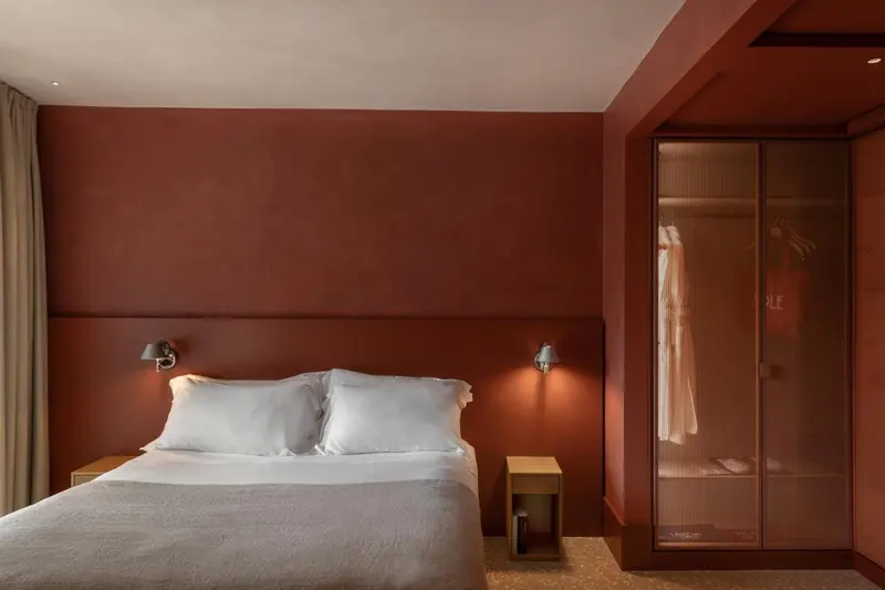 Une chambre à coucher avec un lit blanc et des murs rouges.
