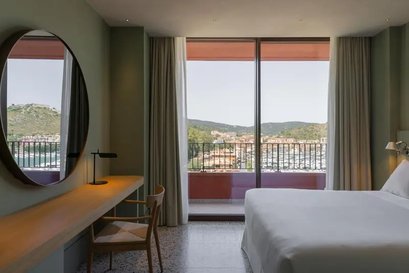 Une chambre lumineuse avec un grand miroir et une vue sur un paysage côtier.