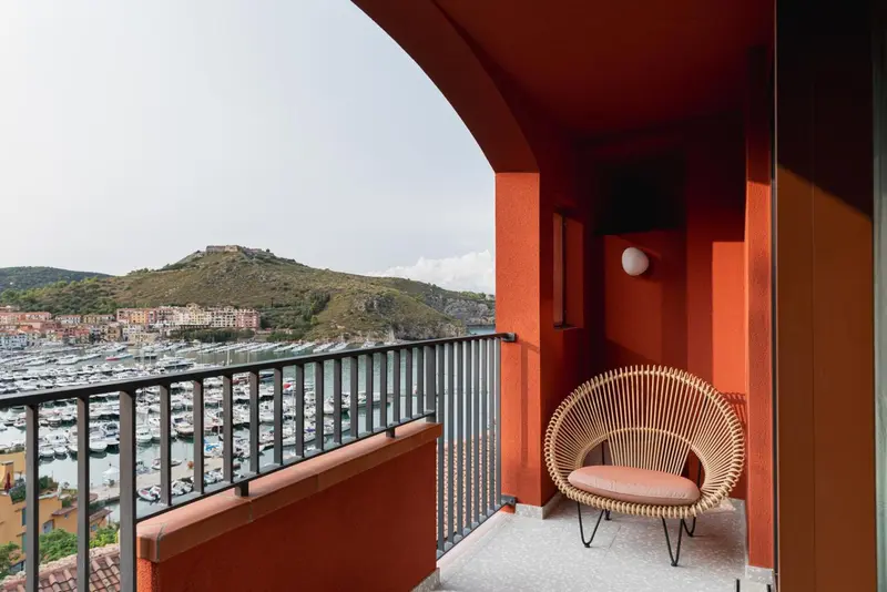Un balcon coloré offre une vue sur un port de plaisance et une colline verdoyante.