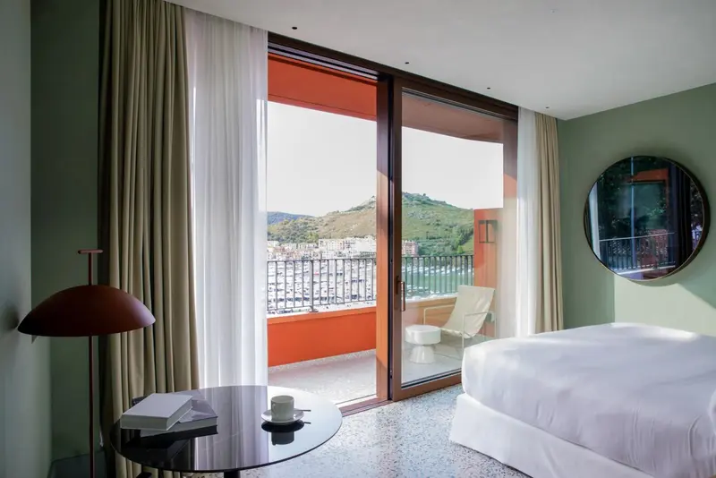 Une chambre lumineuse s'ouvre sur un balcon avec vue sur la mer.