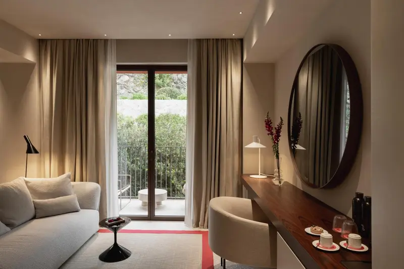 Une chambre lumineuse avec un coin salon et un accès à un balcon.