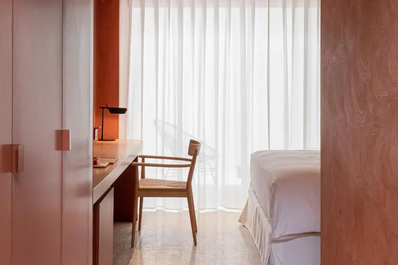 Une chaise et un bureau en bois se trouvent dans une chambre lumineuse.