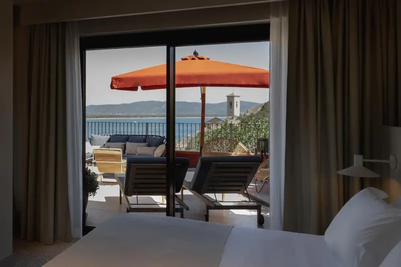 Une chambre lumineuse s'ouvre sur une terrasse avec vue sur la mer.