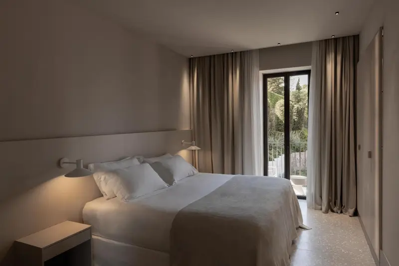 Une chambre lumineuse avec un grand lit et une vue sur la végétation.