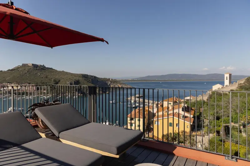 Deux transats sur une terrasse avec vue sur la mer et un paysage côtier.