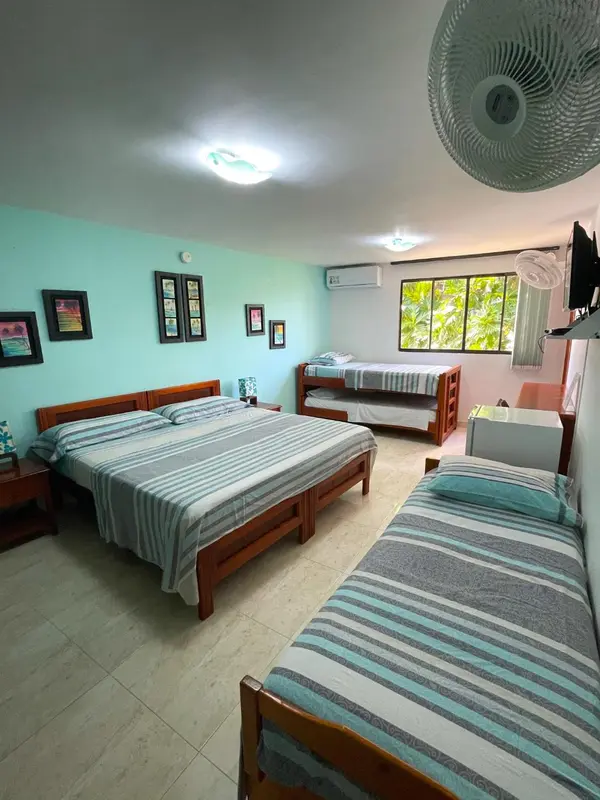Une chambre lumineuse avec deux lits et un lit superposé.