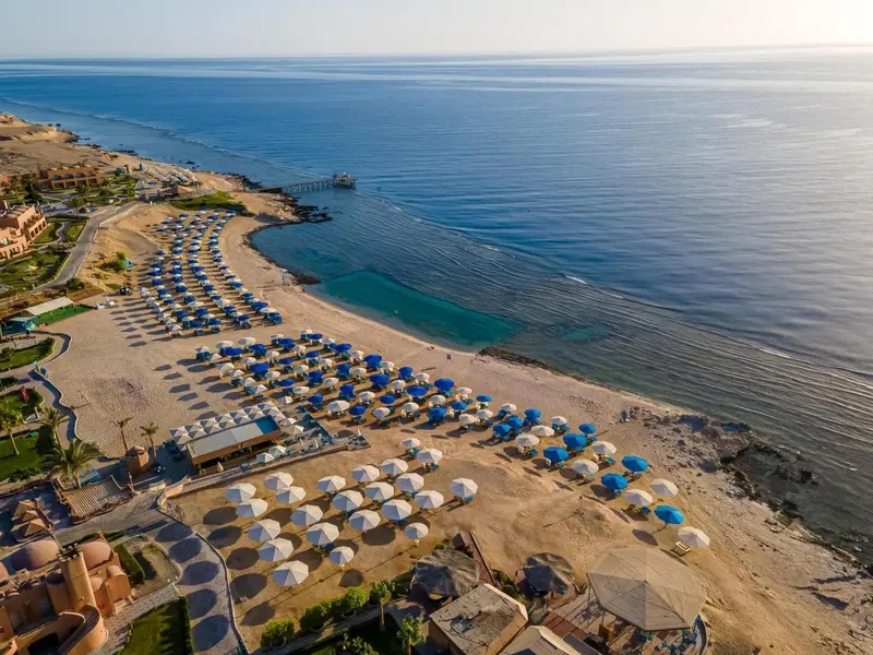 Vue aérienne d'une plage avec des transats bleus et des parasols.