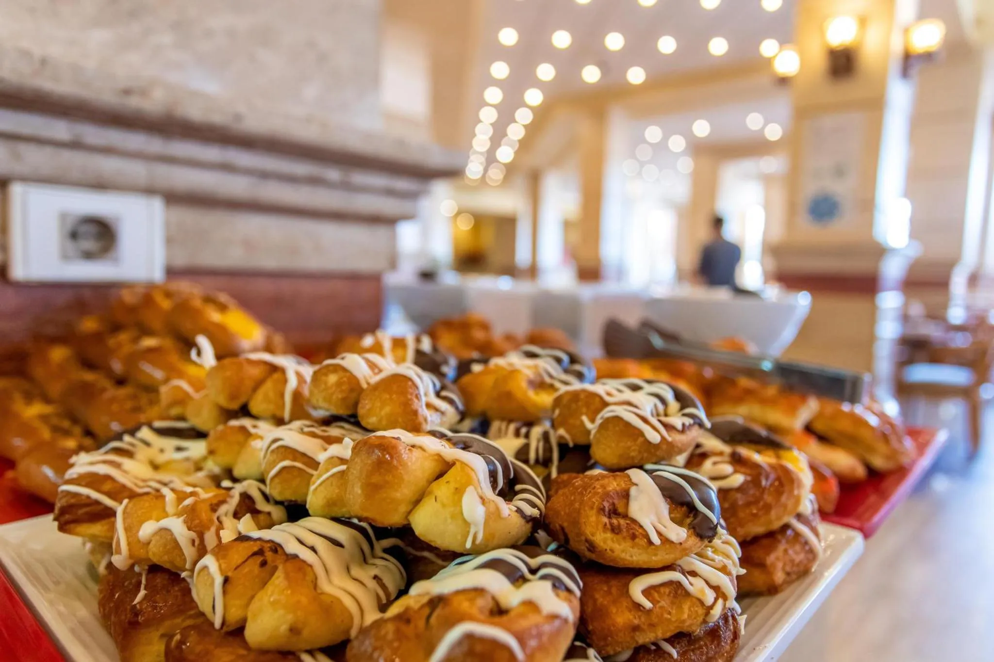 Une table garnie de viennoiseries et de pâtisseries est présentée en buffet.