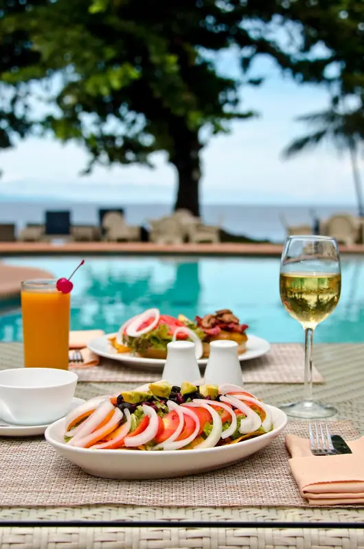 Une table est dressée avec des plats et des boissons au bord d'une piscine.