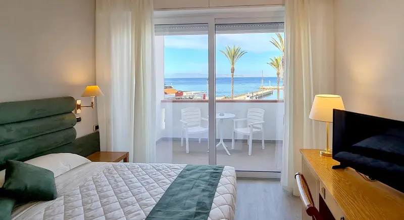 Une chambre lumineuse donne sur une terrasse avec vue sur la mer.
