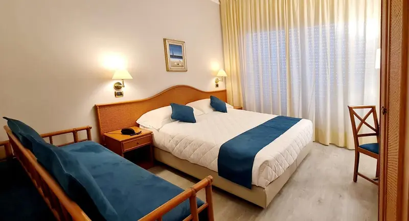 Une chambre lumineuse avec un grand lit et un coin salon.