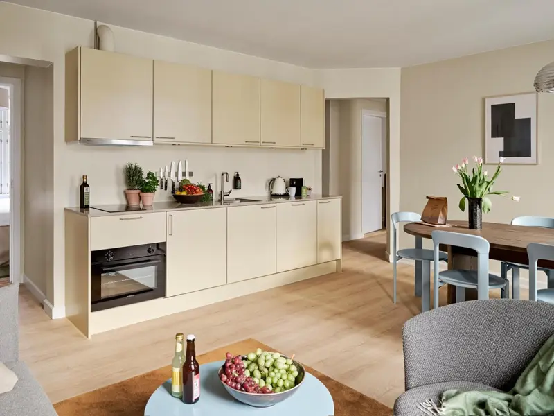 Une cuisine moderne s'ouvre sur un espace repas et un coin salon.