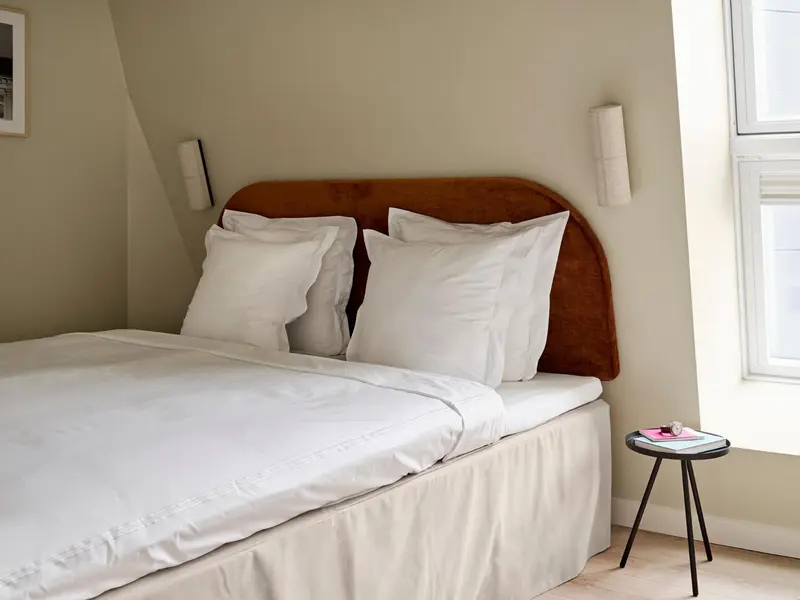Une chambre lumineuse avec un grand lit recouvert de draps blancs.