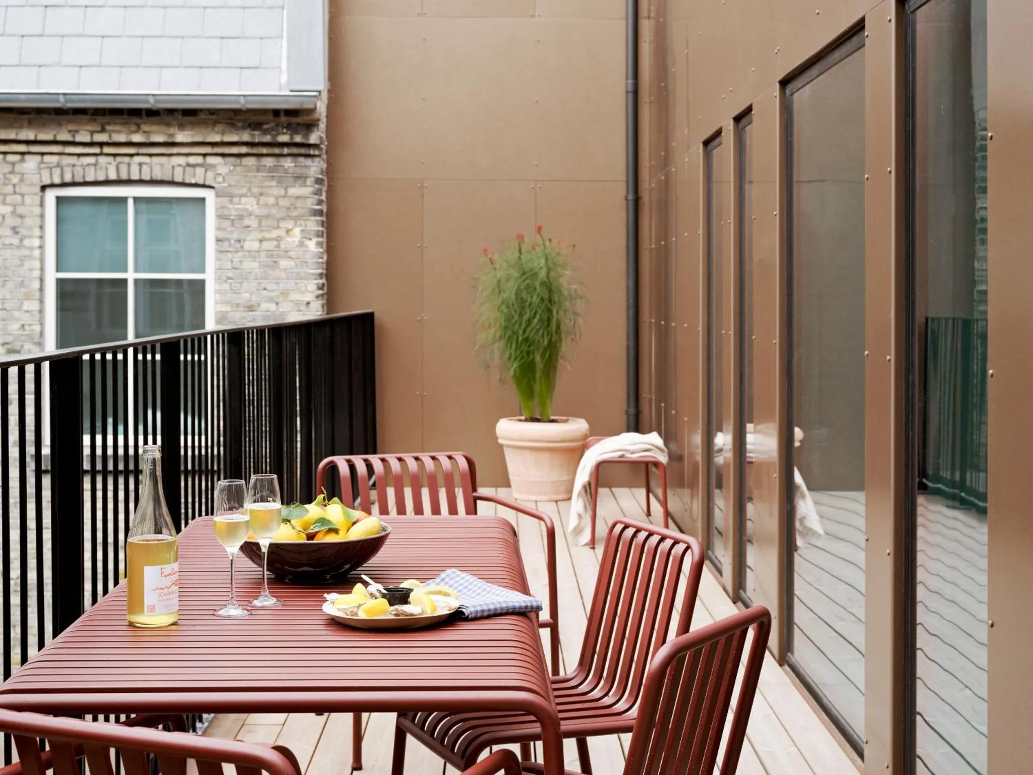 Une table avec des boissons et des fruits est mise en scène sur une terrasse.