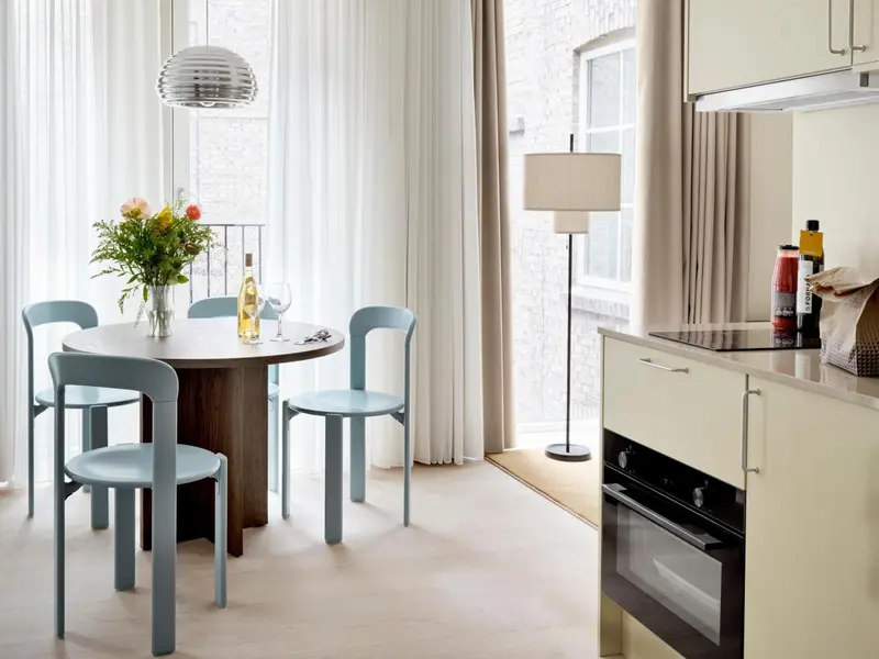 Une table ronde et des chaises se trouvent dans un espace lumineux avec une cuisine équipée.