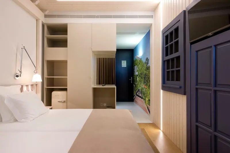 Une chambre lumineuse avec un lit blanc et des rangements intégrés.