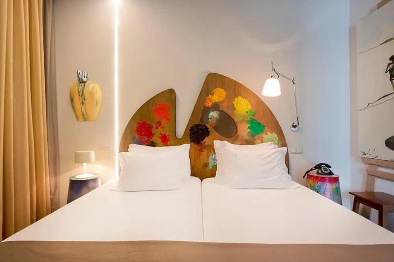 Un lit double avec une tête de lit artistique dans une chambre lumineuse.