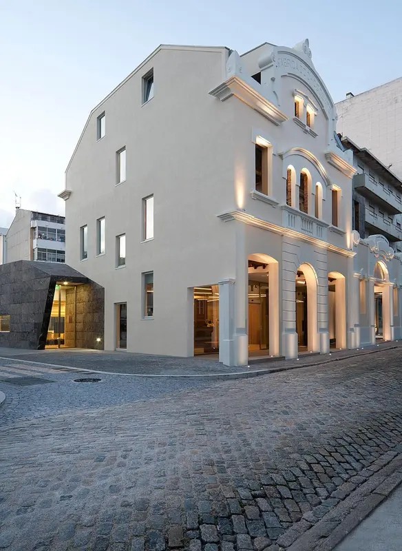 Façade d'un bâtiment beige à plusieurs ouvertures, éclairée par des projecteurs.