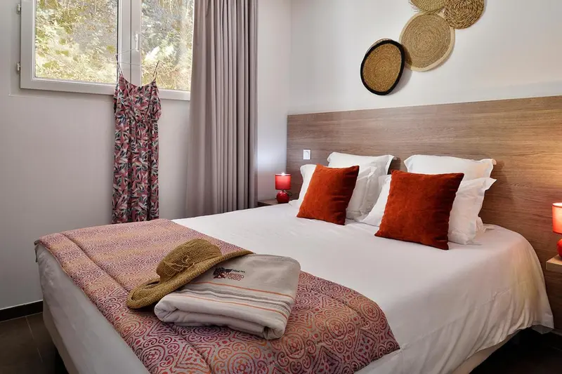 Une chambre lumineuse avec un grand lit recouvert d'une courtepointe colorée et de coussins.